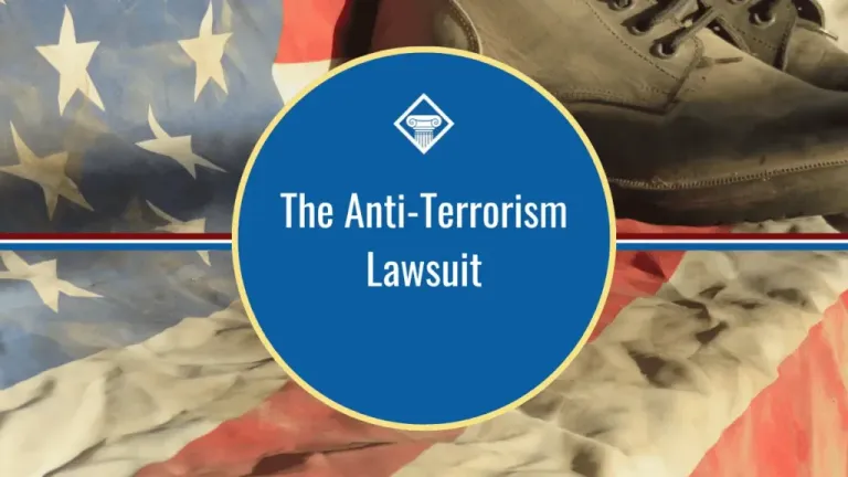 Image of a pair of boots on a weathered American flag. The title of the article, "The Anti-Terrorism Lawsuit" is placed in the middle of the image inside a blue circle with red, white, and blue stripes.