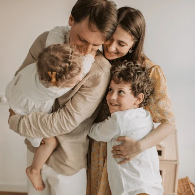 Family of dad, mom, and two kids all hugging and being happy.